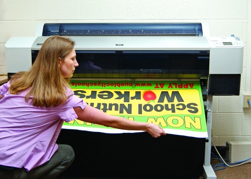 Mary Bocchietti retrieves a banner from the in-plant’s Epson 9800 wide-format printer. 